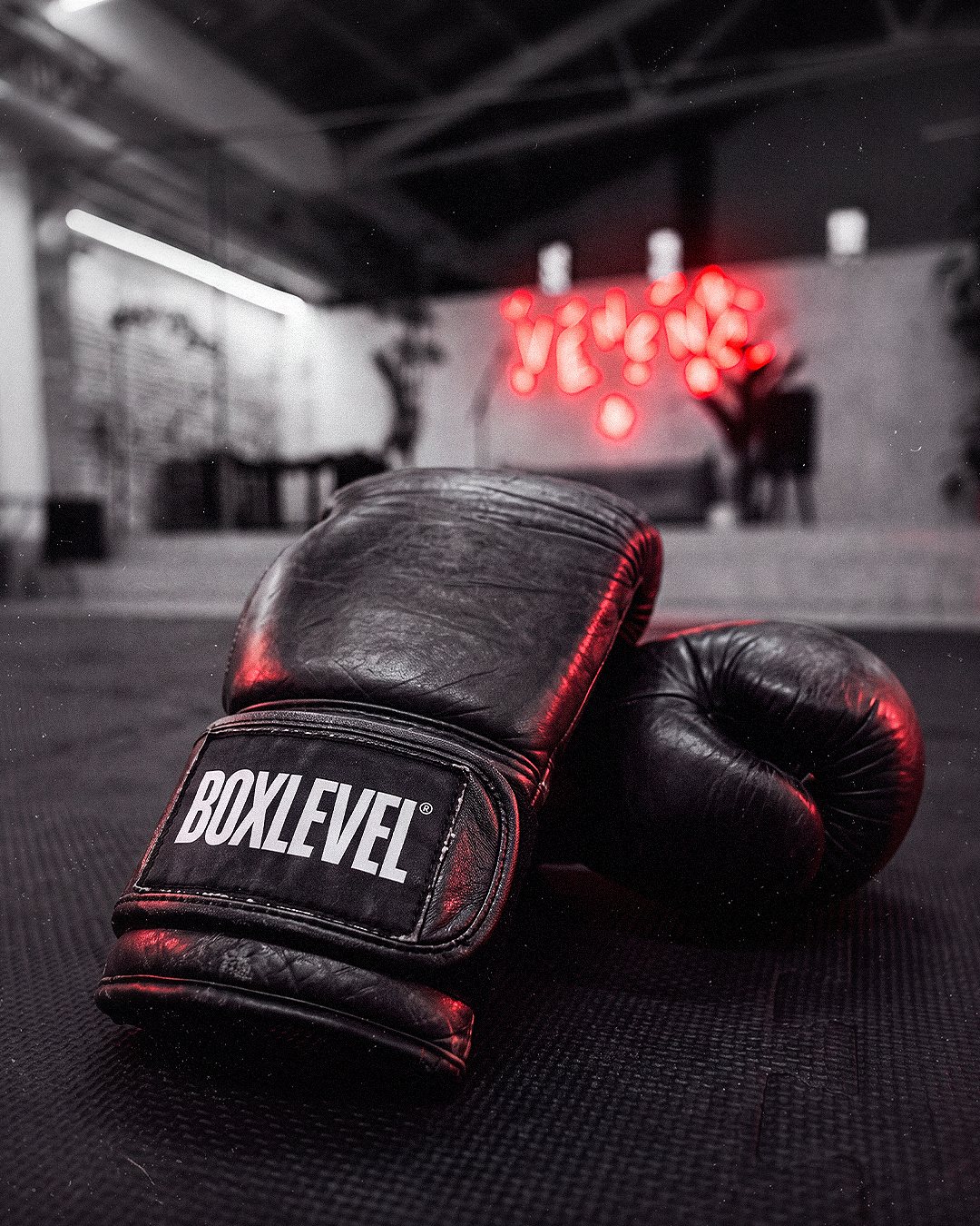 Guantes Boxlevel con el neón de Veneno Concept al fondo